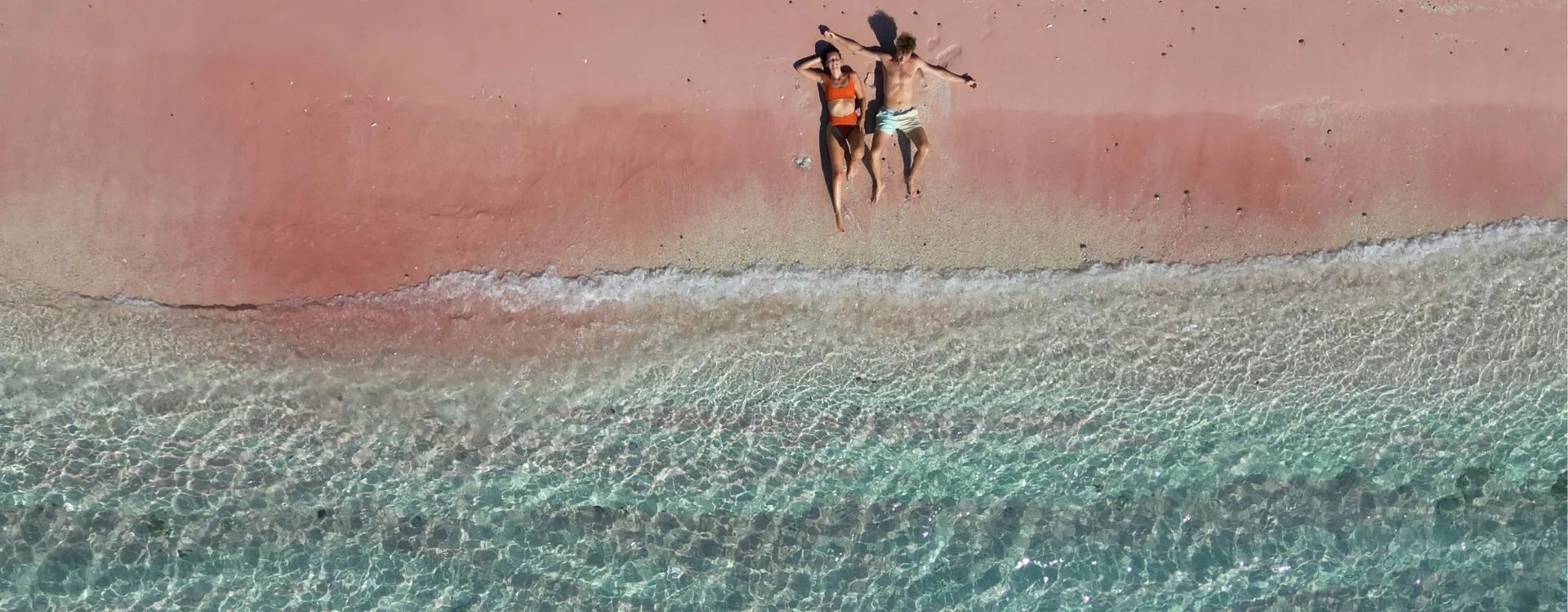 couple lying on pink beach in komodo island indonesia