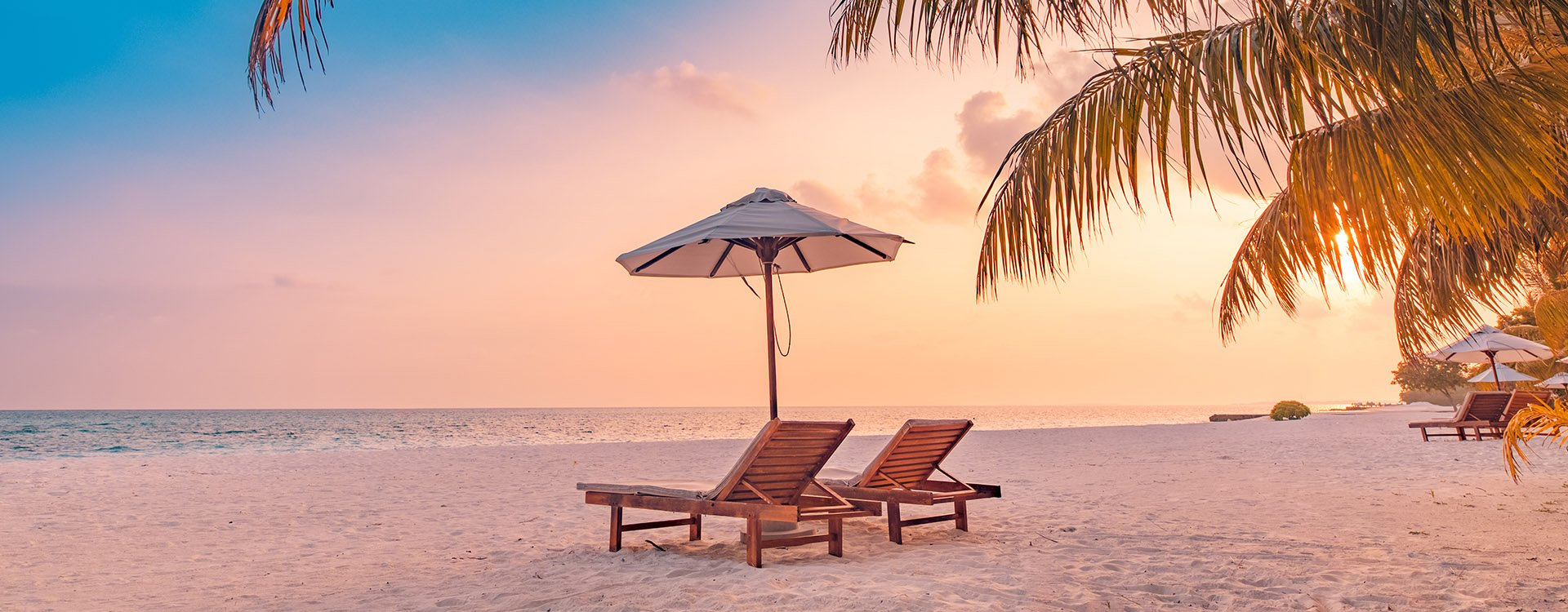 Summer beach landscape. Luxury vacation. Panoramic of sunset beach, two loungers umbrella, palm leaf, colorful sunset sky for paradise island view