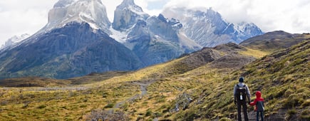 family of two, father and son, enjoying gorgeous view of cuernos del paine in torres del paine national park in chile, active family vacation concept