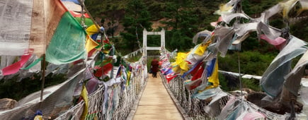 People walk to iron Chain Bridge of Tamchog Lhakhang Monastery, Paro River