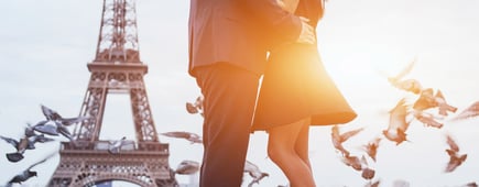 Romantic couple having picnic on grass with wine and fruits near the Eiffel tower in Paris