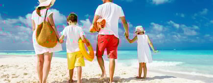 Back view of a happy family at tropical beach on summer vacation