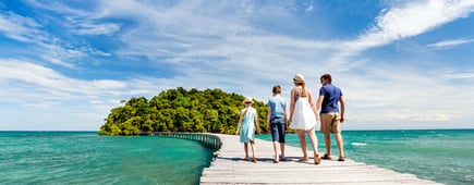 Family walking on wooden pathway leading to beautiful tropical island in Cambodia