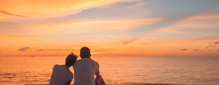 Couple in love watching sunset together on beach travel summer holidays. tropical destination vacation