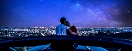Couple watching sunset from popular view point in Los Angeles, California. Sitting on the sport convertible car hood