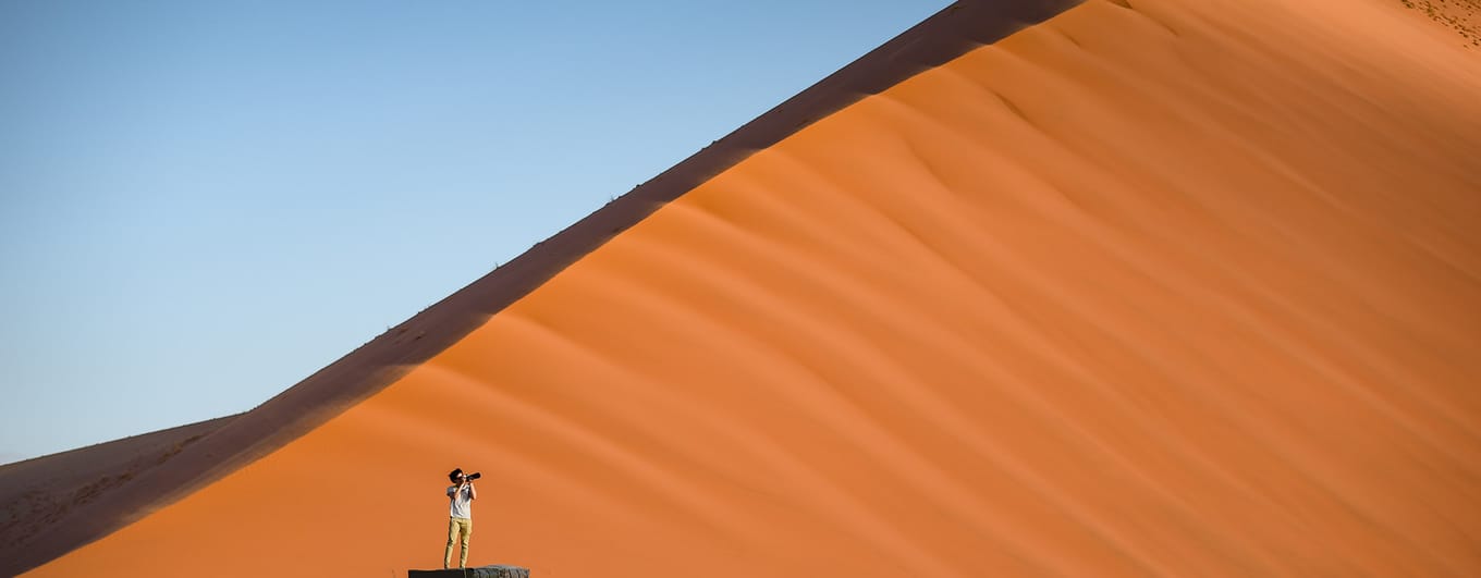 Photographer standing on car in Namibian desert