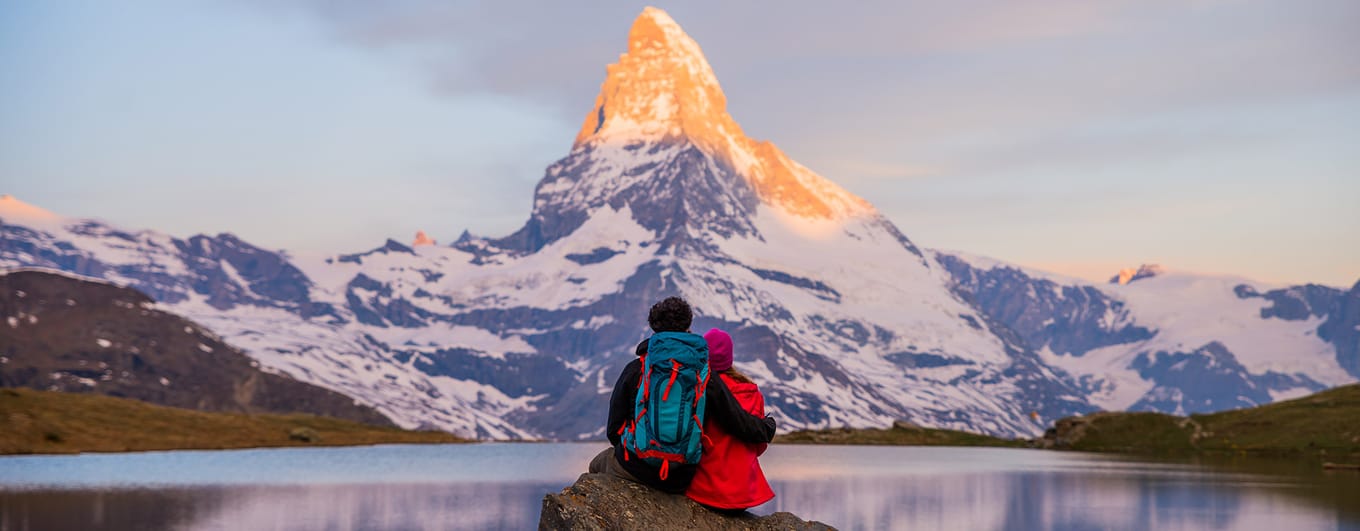 Couple arms around each other watching sunrise on Matterhorn, Switzerland