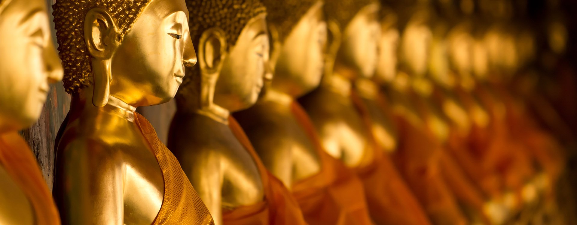 Buddha statues with orange robes in a row at Wat Arun, Bangkok Thailand