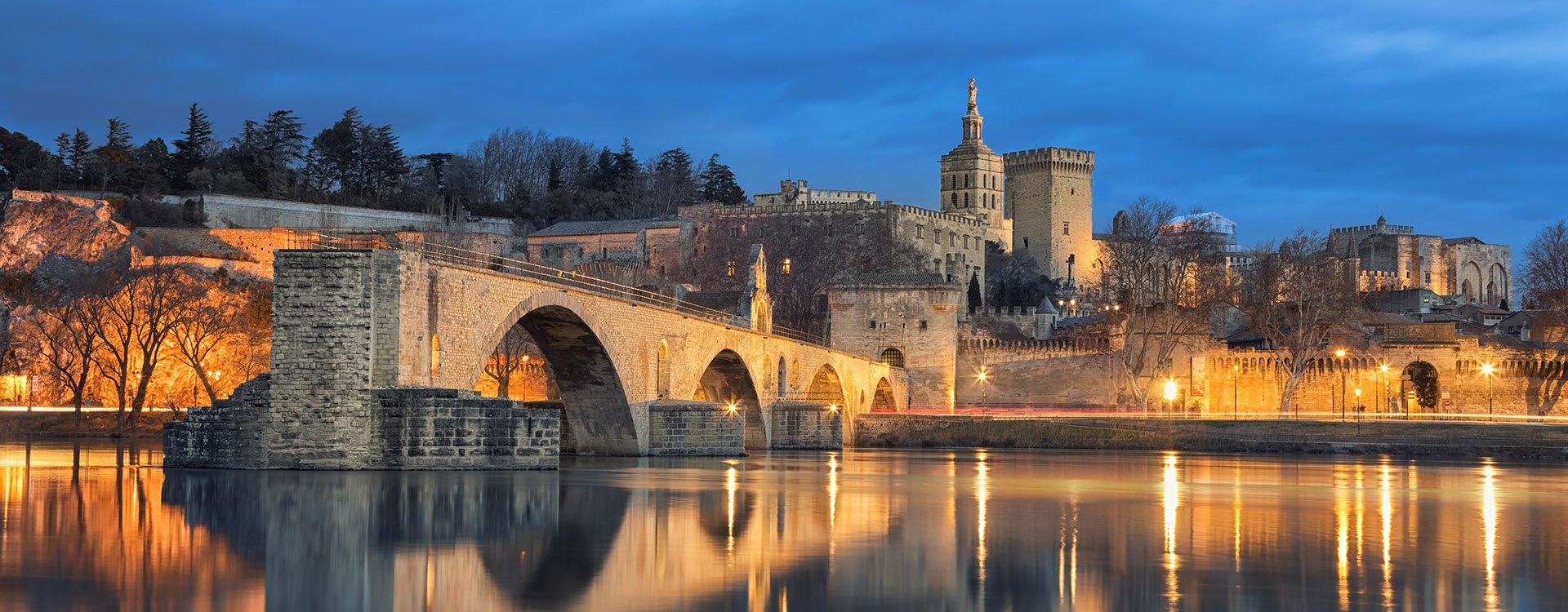 View on Pont d'Avignon 12th century bridge and city skyline reflecting in water at dusk in Avignon, Provence, France