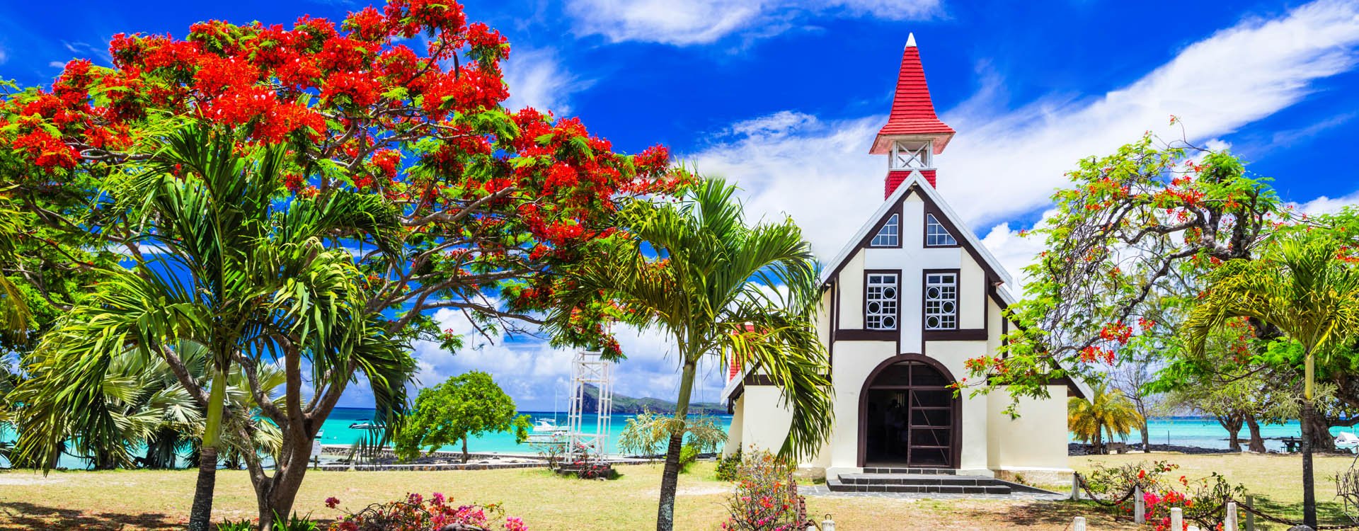 Mauritius island - Red church on the beach with blooming flamboyant tree