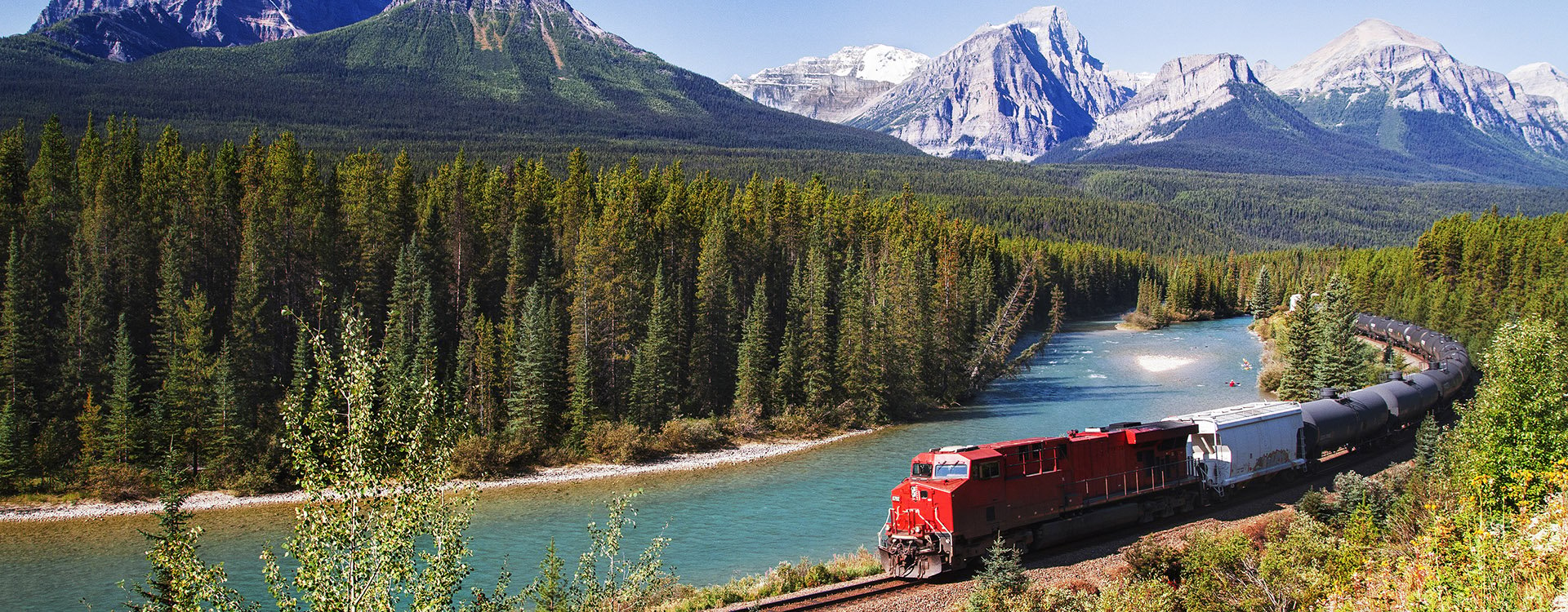 Train passing through Bow valley under the surveillance of mighty Rocky Mountain