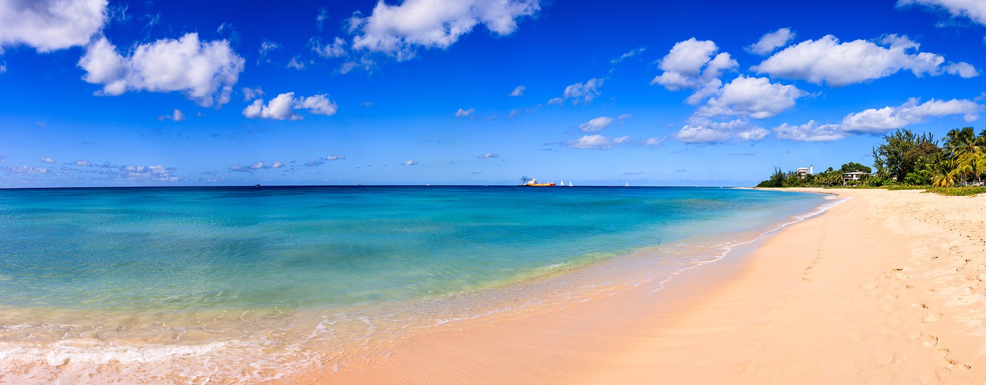 Barbados Island beach, Caribbean. Beach line, white sand, clear turquoise water with small waves and a sunny blue sky