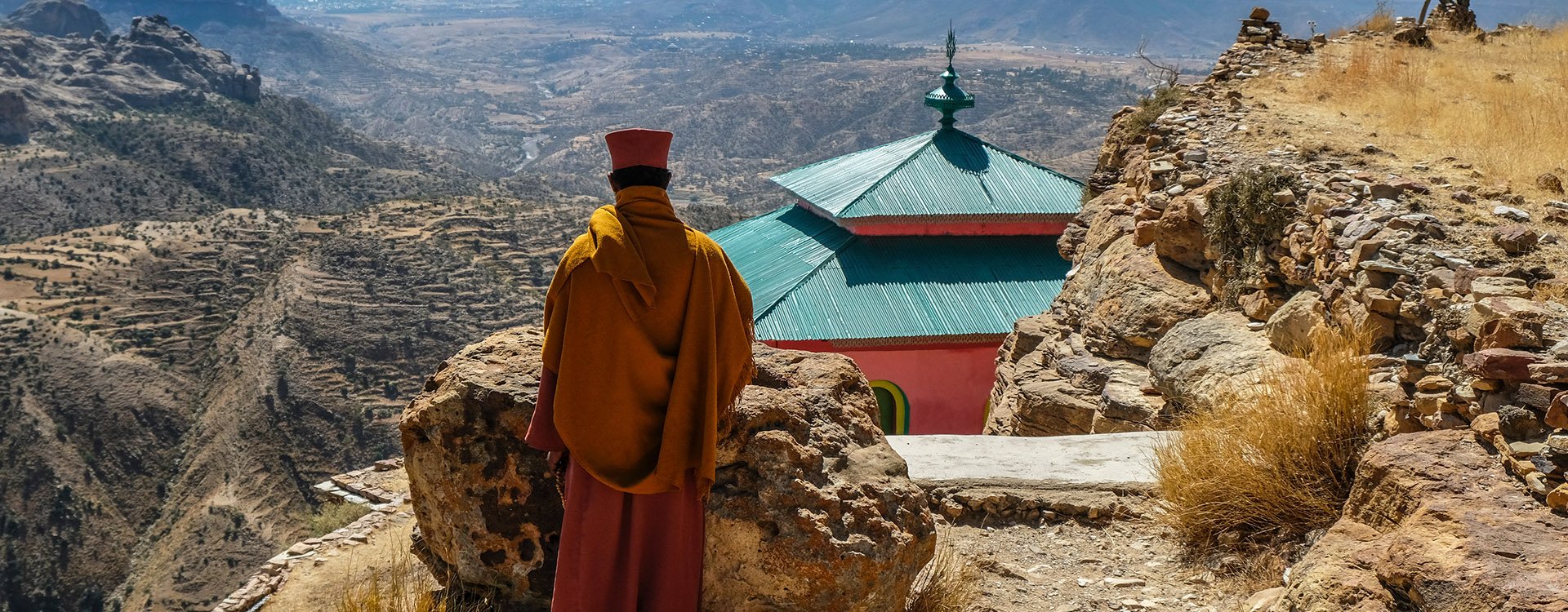Priest looking over scarp at monastery Debre Damo, Ethiopia.