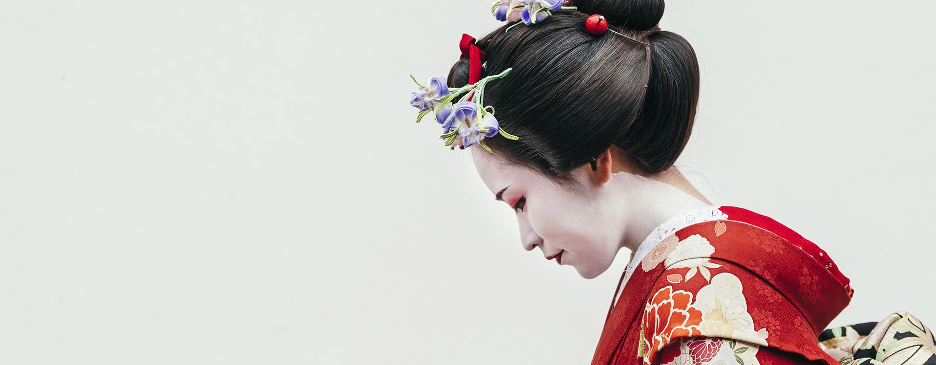 Portrait of a Maiko geisha in red floral kimono in Gion Kyoto