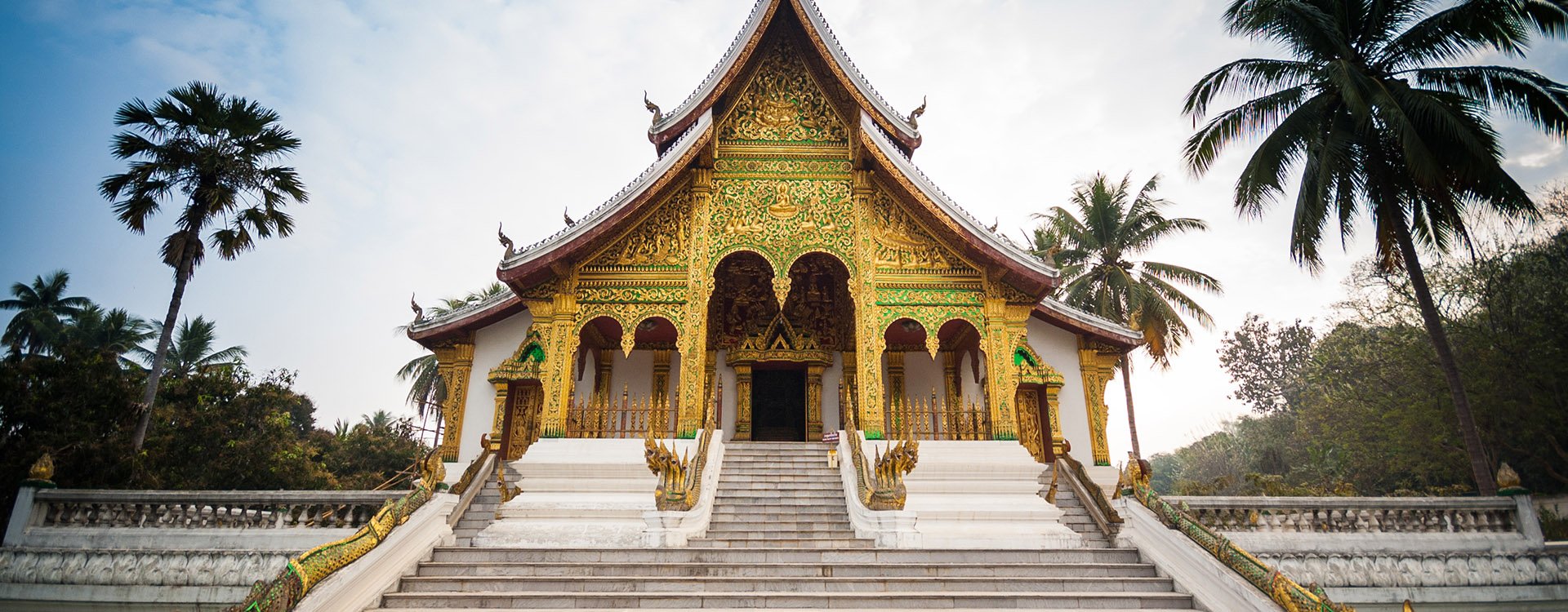 White stairs with dragon railings to golden entrance ofLuang Prabang Royal Palace, Laos