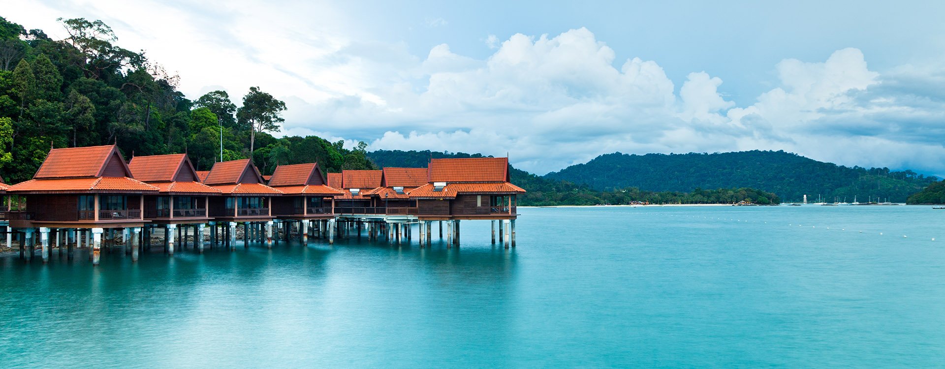 Luxury hotel bungalows on stilts over clear blue water, Langkawi Island, Malaysia