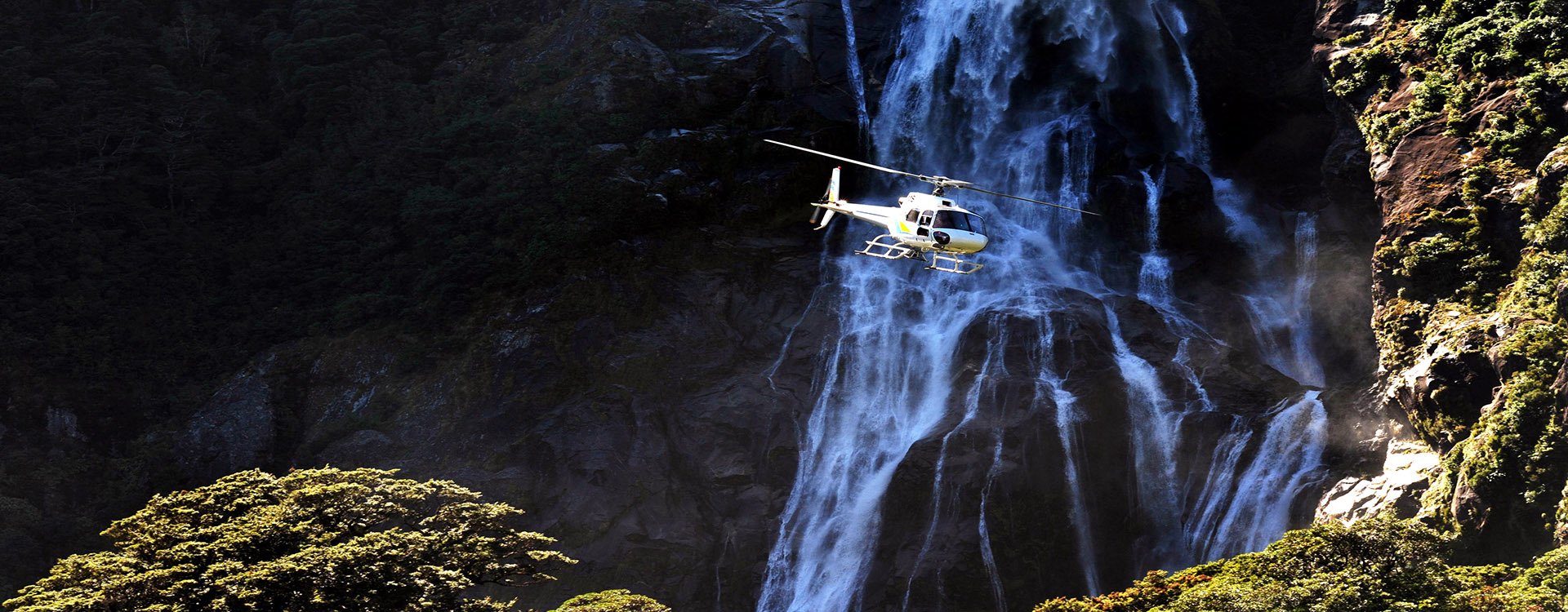 New Zealand_A helicopter flying over a waterfall in Fiordland national park in the South Island