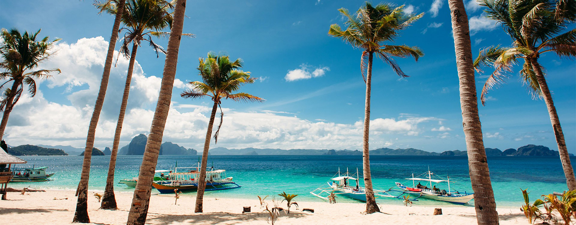Tropical beach with palm trees, boats, blue sky and white sand Philippines, El Nido
