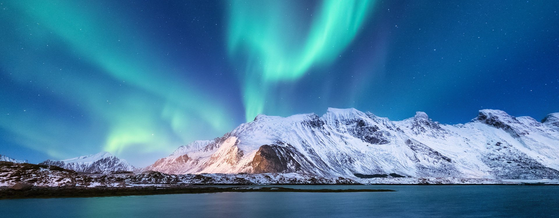 Aurora borealis, Green northern lights above mountains. Night sky with polar lights. Night winter landscape with aurora and reflection on the water surface.