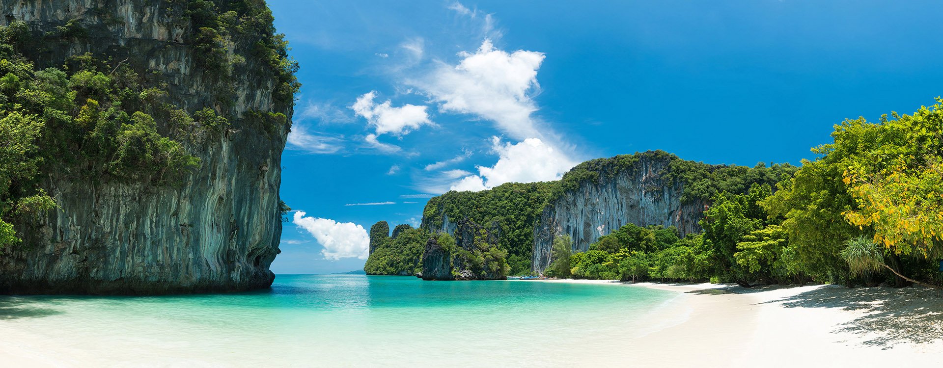 White sand beach and rock formations with clear blue waters at southern island of Thailand