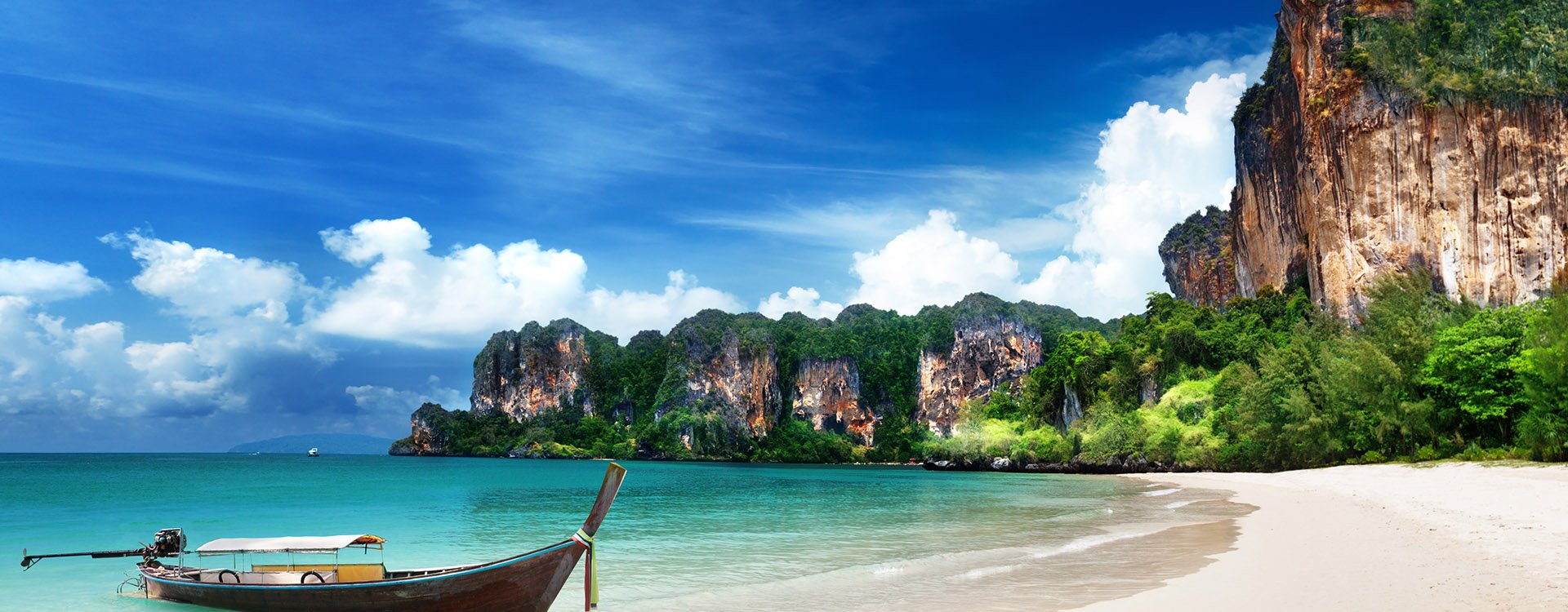 Railay beach, natural rock formations and clear blue waters and sampan boat in Krabi Thailand