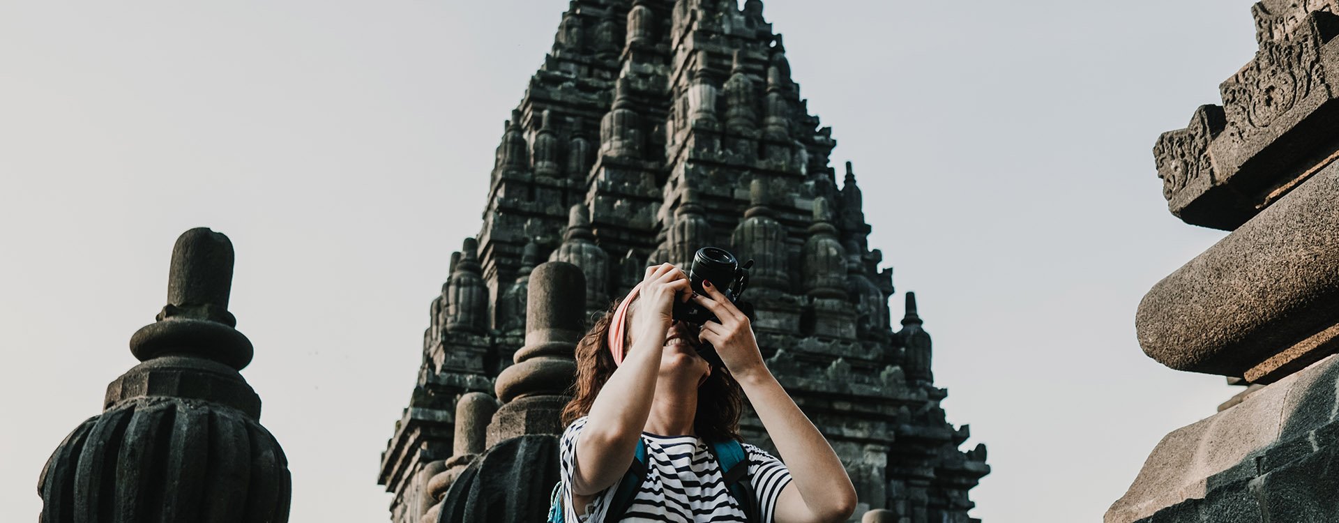 Upwards shot of woman photographing Prambanan Temple, Java