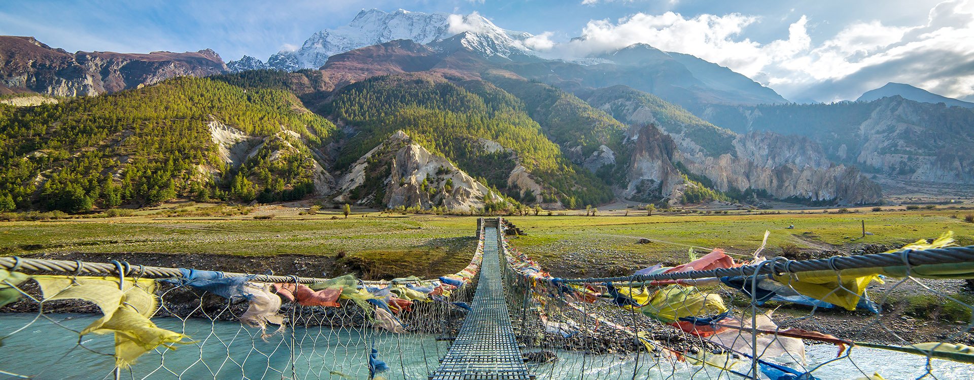 Prayer flags covered bridge leading to mountains Annapurna, Nepal