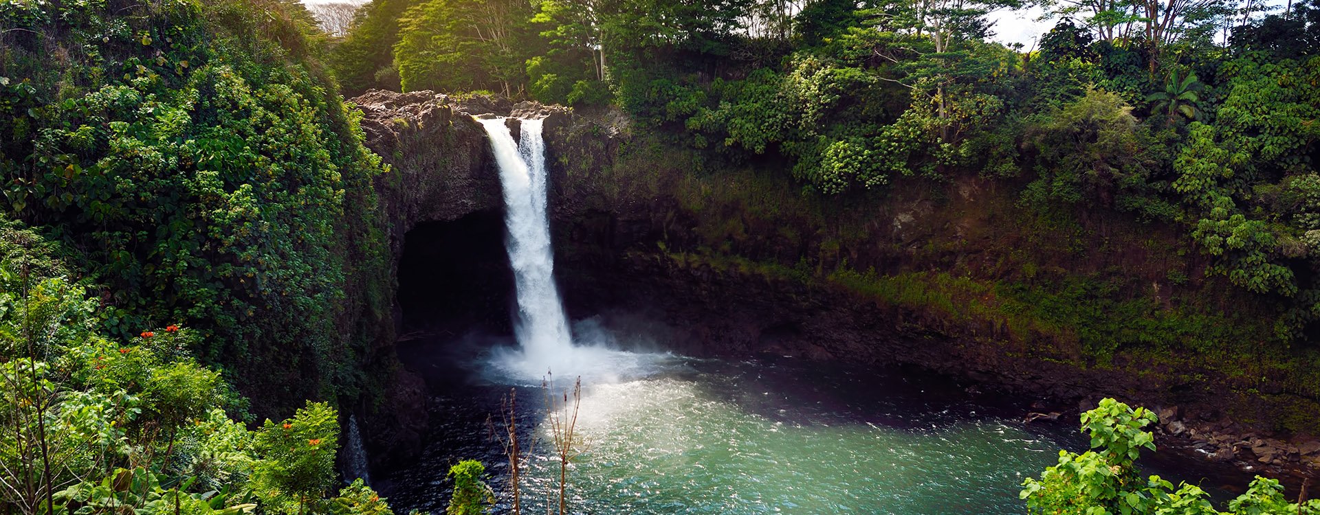 Majesitc Rainbow Falls waterfall in Hilo, Wailuku River State Park, Hawaii. Nnatural lava cave, the mythological home to Hina, an ancient Hawaiian goddess