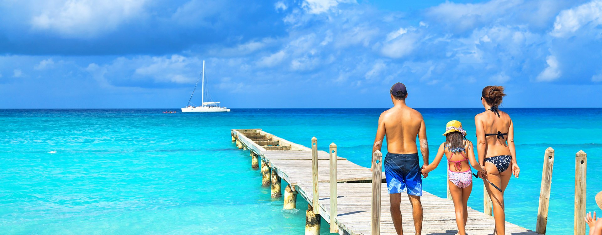 Back view of a happy family on tropical beach. Family standing on a wooden pier.