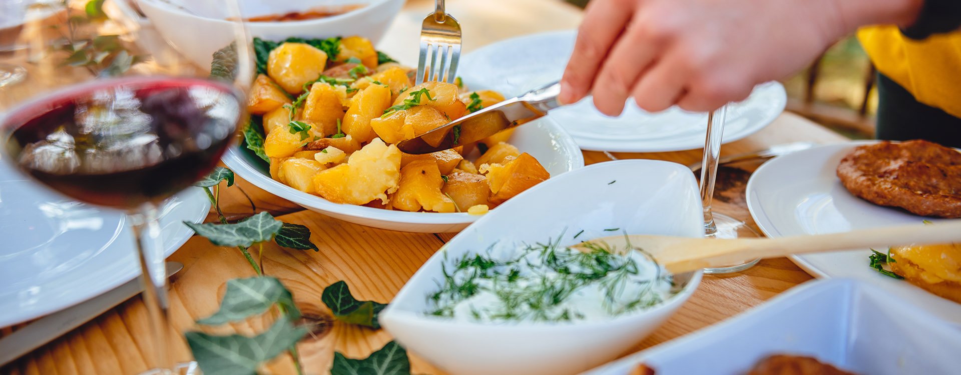 Close up photo of woman serving roasted potato at family lunch in backyard patio