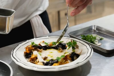 A chef at Domaine De Primard Hotel plating a dish