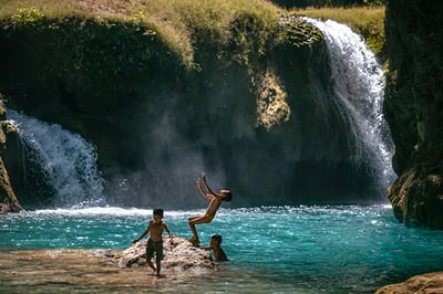 children playing in a waterfall sumba indonesia