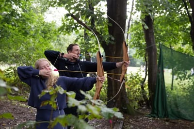two people doing archery in the woods