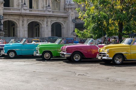 2 American green Chevrolet classic car drives on the main road in Havana Cuba City before the Capitolio - Serie Cuba Reportage