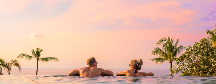 Romantic couple looking at beautiful sunset in luxury infinity pool