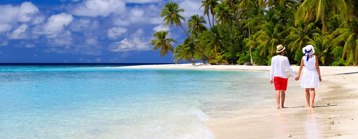 happy loving couple walking on summer tropical beach