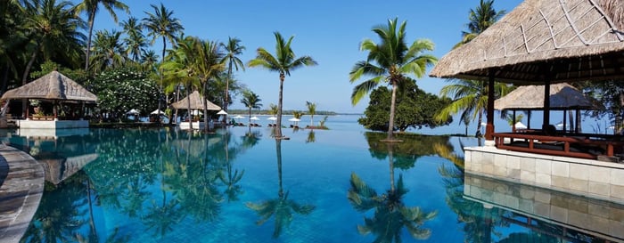 Tranquil infinity pool and beach in the background at Oberoi Lombok