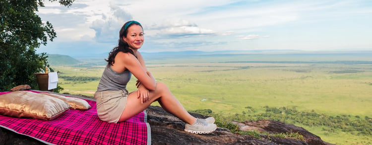  ? A woman sitting on a rock in the Maasai Mara 