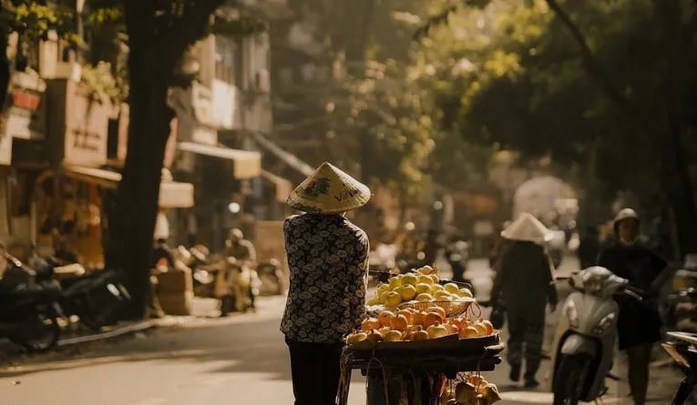 Woman walking with oranges in Hanoi