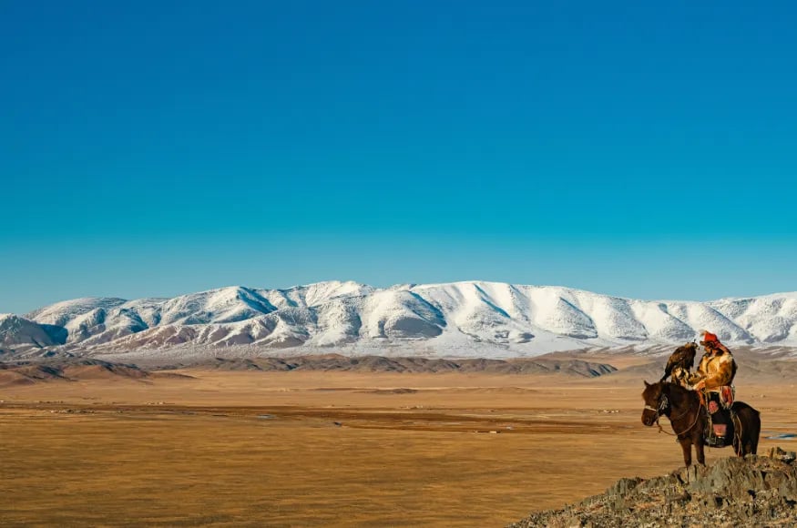 A man on a horse with Mongolian landscapes in the background