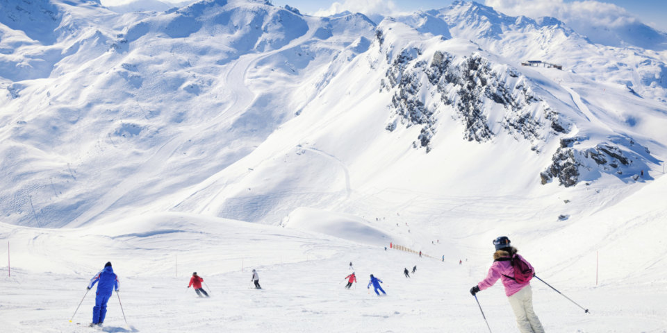 People skiing down a red piste at the Alpine resort of Meribel in the Three Valleys (Trois Vallees) in France.